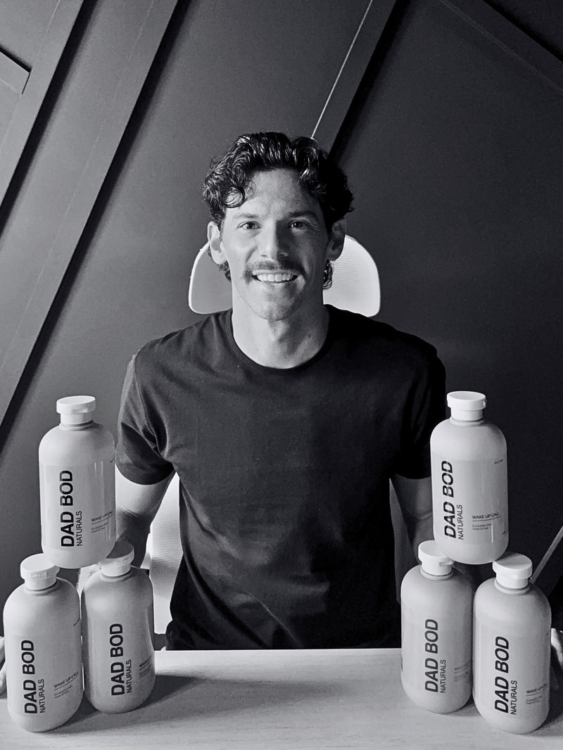 Mat sitting behind a table with 'DAD BOD' bottles in a black and white setting